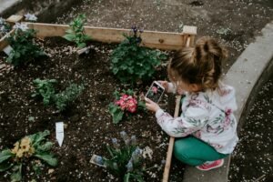 A little girl taking photo of their house garden .